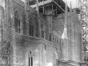 An array of rooflines suggests subtly the convex refinement of the chancel cornice at upper left. This northeast view also follows the progress of the tower stairs from the transept turret up a straight flight past three narrow lancets, to spiral again up the free standing tower, here just under construction.